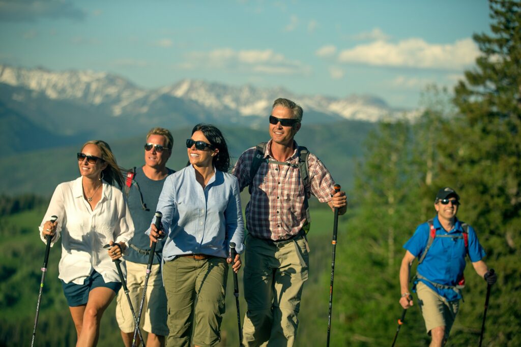 five adults and one child walking on a forest trail with mountains